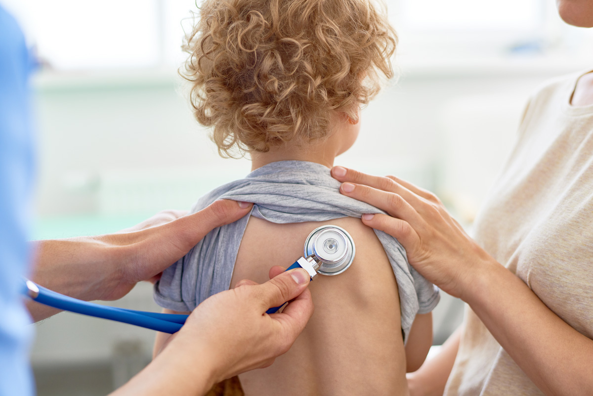 A pediatric doctor using a stethoscope on a child’s back in Oak Lawn.